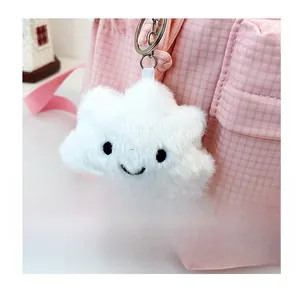 Close-up of white plush cloud keychain with cute smile and striped legs on a pink bag