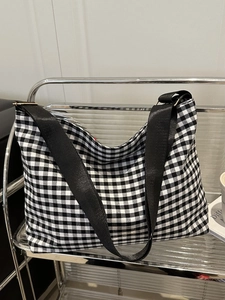 Detailed close-up of checkered canvas bucket bag hanging on a modern metal shelf