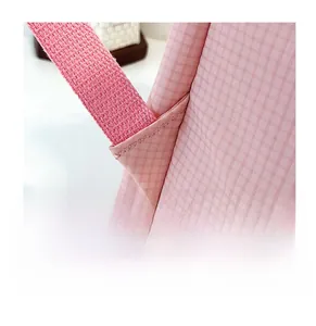 Detail of pink plaid backpack shoulder strap with reinforced stitching on white background