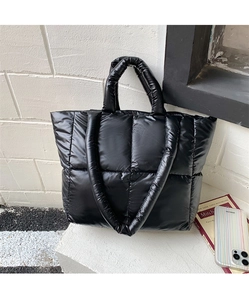 Detail of black puffer tote bag showing quilted texture and soft handles for daily commute