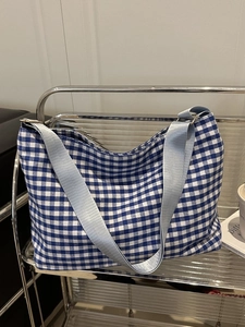 Close-up of blue and white checkered canvas tote bag with wide nylon shoulder straps