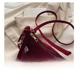 Détail du sac sous l'aisselle en velours bordeaux avec zip doré et breloque lapin