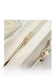 Detail shot of white crocodile pattern tote bag featuring a smooth gold metal zipper closure