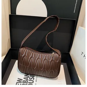 Detail of a brown pleated shoulder bag with metal zipper inside a black luxury gift box