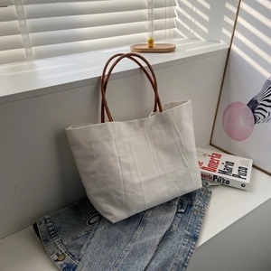 Minimalist cream canvas bucket bag with brown leather handles and striped texture