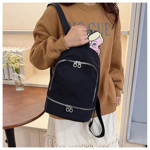 Détail du sac à dos en nylon noir imperméable montrant les fermetures éclair argentées et sangles