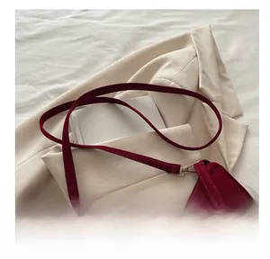 Détail du sac bandoulière en velours bordeaux avec des breloques métalliques argentées