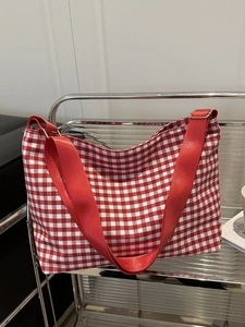 Detail of red and white gingham canvas bucket bag with adjustable nylon shoulder strap