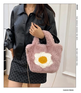 Detail of pink plush tote bag with egg patch and golden metal chain strap