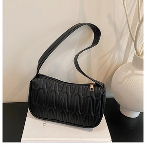 Detail of black wave-quilted shoulder bag featuring premium texture and gold zipper