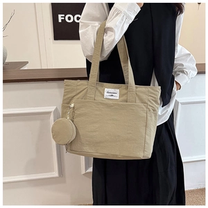 Detail of khaki tote bag showing canvas texture, front pocket, and round coin purse