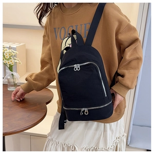 Détail du sac à dos noir minimaliste avec poches zippées doubles et finitions métalliques