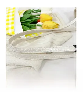 Close-up detail of white crocodile pattern tote bag strap with elegant floral decoration