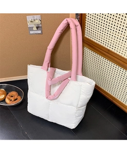Detail of white quilted tote bag featuring vibrant pink puffy shoulder handles and soft texture