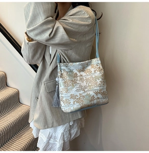 Detail of landscape embroidery on silk tote with elegant grey tassel and slim strap