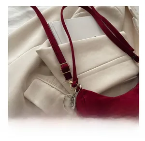Détail du sac à bandoulière en velours bordeaux avec sangle réglable et boucle dorée