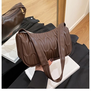 Detail of dark brown quilted shoulder bag with vertical wavy pleats and gold zipper