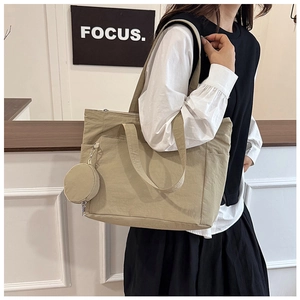 Detail shot of a khaki nylon tote bag with a small round pouch and long shoulder straps