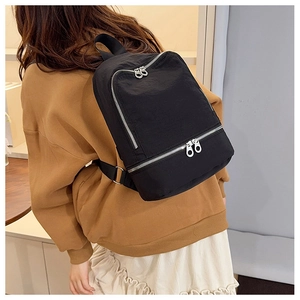 Détail du sac à dos minimaliste en nylon noir avec fermetures éclair doubles argentées