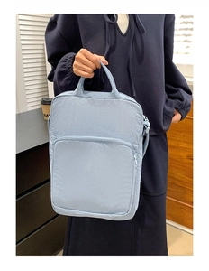 Dettaglio della borsa azzurra in tessuto oxford con trama impermeabile e tasche a cerniera