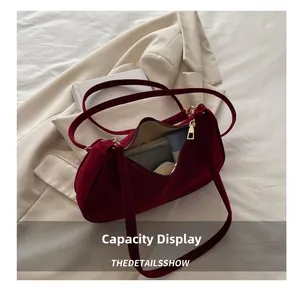 Capacité intérieure du sac d'épaule en velours bordeaux avec objets du quotidien et zip doré