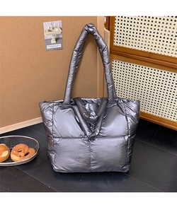 Detail of silver quilted tote bag with metallic finish and padded dual handles