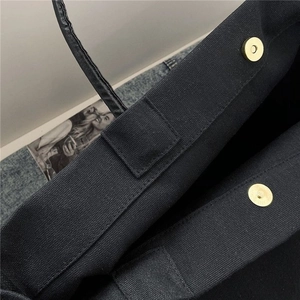 Close-up of black canvas bucket bag featuring magnetic snap closure and reinforced stitching