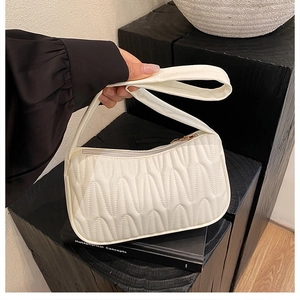 Close-up of white pleated shoulder bag with vertical quilting and gold zipper detail