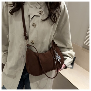 Détail du sac hobo mat marron foncé avec un pendentif papillon argenté et une bandoulière