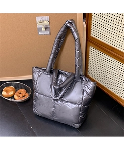 Macro shot of silver metallic quilted tote bag showcasing fabric texture and wide straps