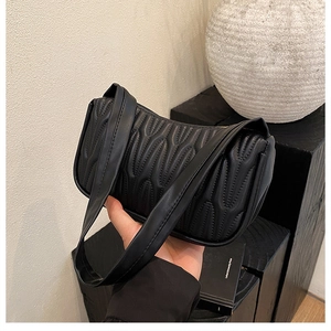 Detail of black quilted leather shoulder bag with vertical pleats and curved silhouette