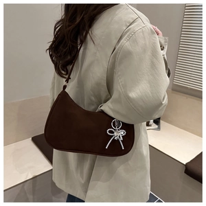 Détail du sac hobo en daim marron foncé avec un pendentif nœud argenté et perle