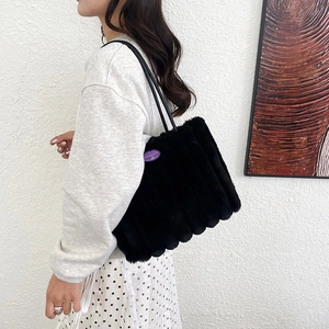 Dettaglio della borsa tote di peluche nera con etichetta ciliegia viola in stile di vita