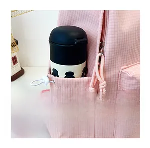 Detailed view of the pink checkered backpack side pocket with a drawstring and water bottle