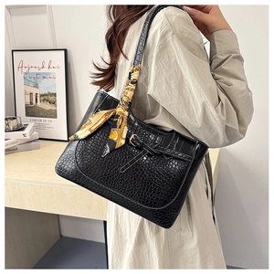 Detail of black faux leather tote with crocodile texture and decorative silk scarf on strap
