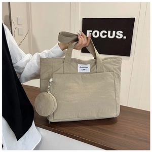 Close-up of khaki canvas tote bag with front pocket and round zipper pendant detail