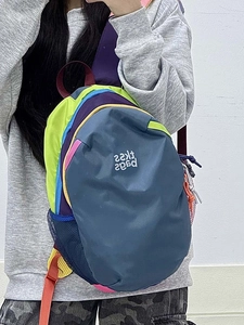 Mirror selfie showing the colorful patchwork backpack with side mesh pocket and red straps