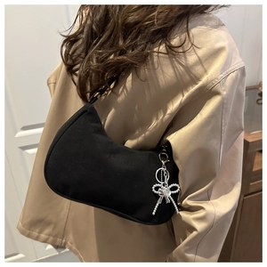 Détail du sac croissant noir avec pendentif cœur en forme de nœud argenté et fini mat