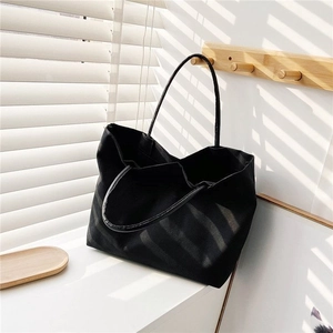 Detail of minimalist black canvas bucket bag showing large capacity and natural light shadows