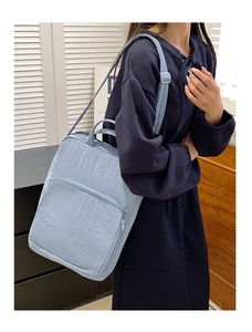 Primo piano di una borsa tote in nylon celeste indossata da una modella in interno