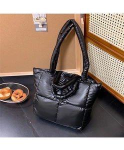 Detailed macro view of black quilted puffer tote bag with glossy water-resistant finish