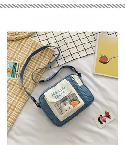 Détail du sac bandoulière en toile bleue avec poche PVC et lapin en peluche