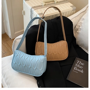 Detailed view of sky blue and khaki underarm bags with unique wavy quilted texture