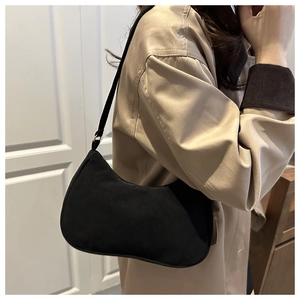 Détail du sac sous l'aisselle en daim noir avec boucle dorée et forme de croissant chic