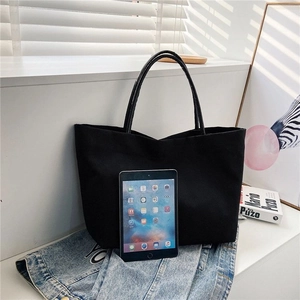 Detailed view showing the large capacity canvas bucket bag with iPad for size reference