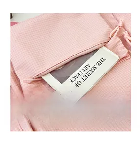 Close-up of pink checkered fabric backpack featuring a functional front zipper pocket