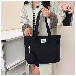 Detail of black canvas tote bag with a small matching round pouch and white woven label