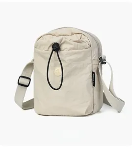 Vista laterale macro di una mini borsa a tracolla beige in nylon con trama e etichetta