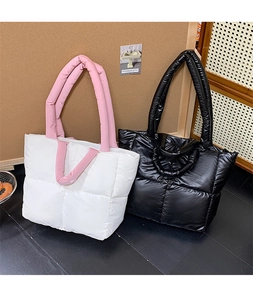 Close-up showing the fluffy quilted texture of two large puffer tote bags in white and black