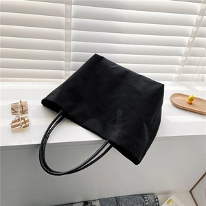 Detail view of a black canvas bucket bag with handles on a white window ledge